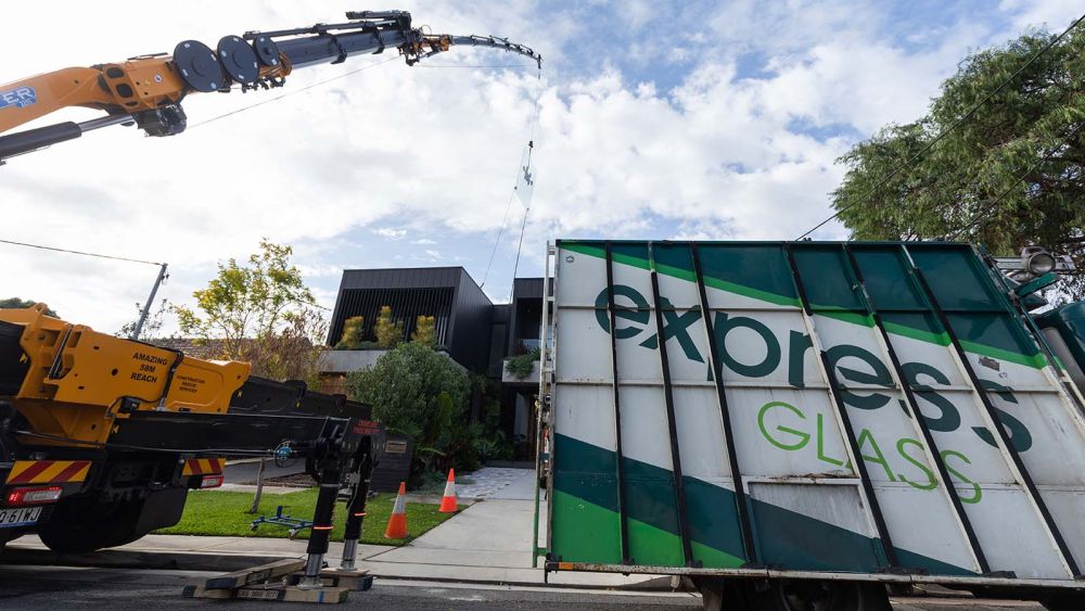 A crane is lifting glass from an Express Glass truck at a modern house in Matraville, Sydney.